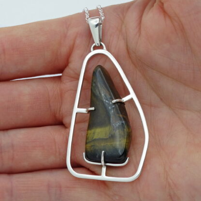 Tiger's eye silver pendant presented in the palm of a hand