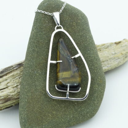 Tiger's eye silver pendant presented on a pebble