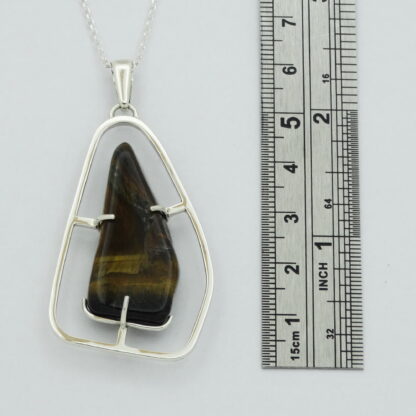 Tiger's eye silver pendant with a ruler for scale