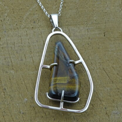 Tiger's eye silver pendant presented on a woodgrain background