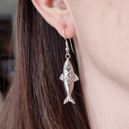 Silver mackerel earrings worn on the ear