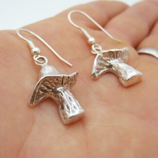 Silver mushroom earrings presented in the palm of a hand