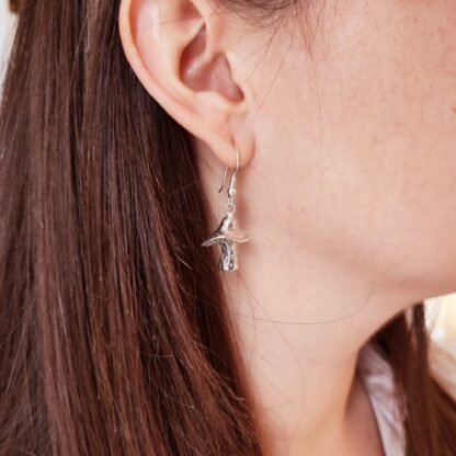 Silver mushroom earrings worn on the ear