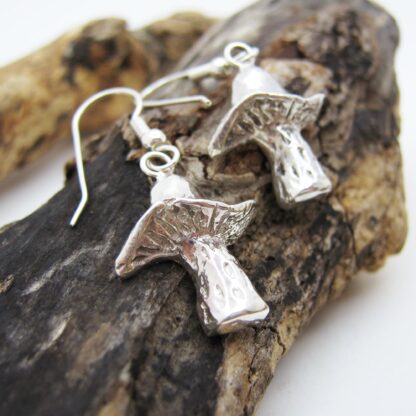 Silver mushroom earrings presented on a log