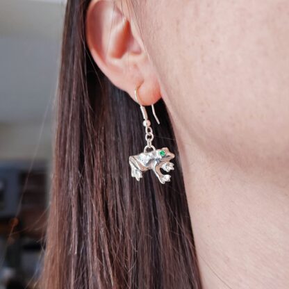 Silver frog earrings worn on the ear